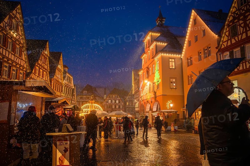 People with umbrellas strolling through the Christmas-lit old town market at night, Christmas market Calw, Black Forest, Germany, Europe
