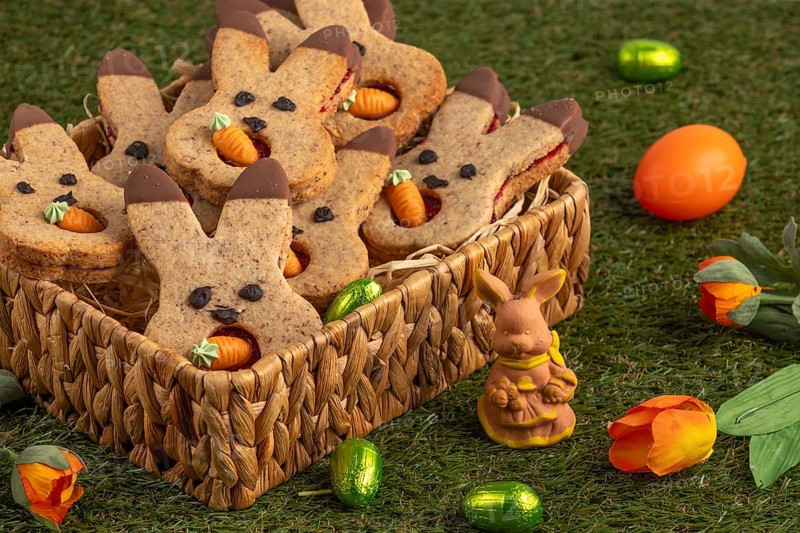 Bunny biscuits in a basket next to Easter decorations in a meadow