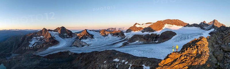 Panorama, atmospheric sunrise in a picturesque mountain landscape, alpenglow, aerial view, mountaineer on the summit of Becher and Übeltalferner glacier, Stubai Alps, South Tyrol, Italy, Europe