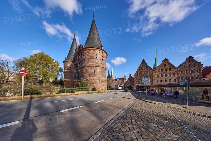 Lübeck Holstentor, side view, pedestrian crossing, cobblestone pavement, blue sky with fair weather clouds, intersection Wallstraße with Holstentorplatz, Hanseatic city of Lübeck, Schleswig-Holstein, Germany, Europe