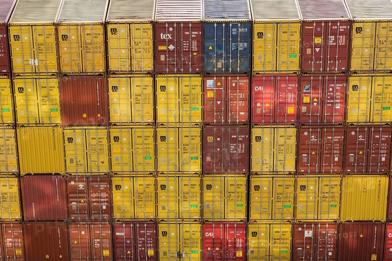 High angle view of stacked yellow and reddish brown MSC, TEX and CAI metal box shipping containers on dock in La Spezia cargo Port, Italy, Europe