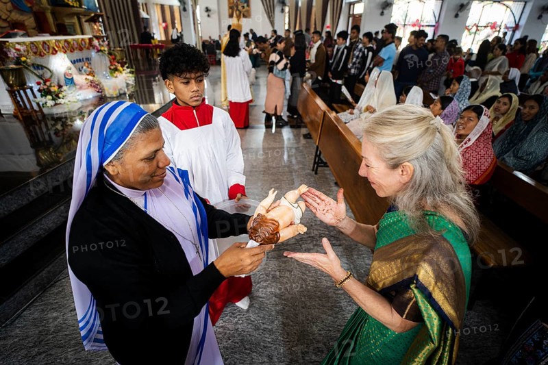 A priest holds an idol of baby Jesus Christ as devotees kiss the idol during a Christmas day sermon on December 25, 2024 in Guwahati, India. Christmas is a festive holiday celebrated on December 25th, marking the birth of Jesus Christ in Christian tradition.
