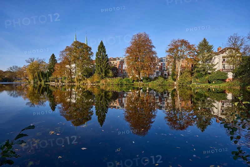Mill pond with trees, general buildings against a cloudless blue sky, symmetrical reflections on the water surface, Hanseatic city of Lübeck, Schleswig-Holstein, Germany, Europe