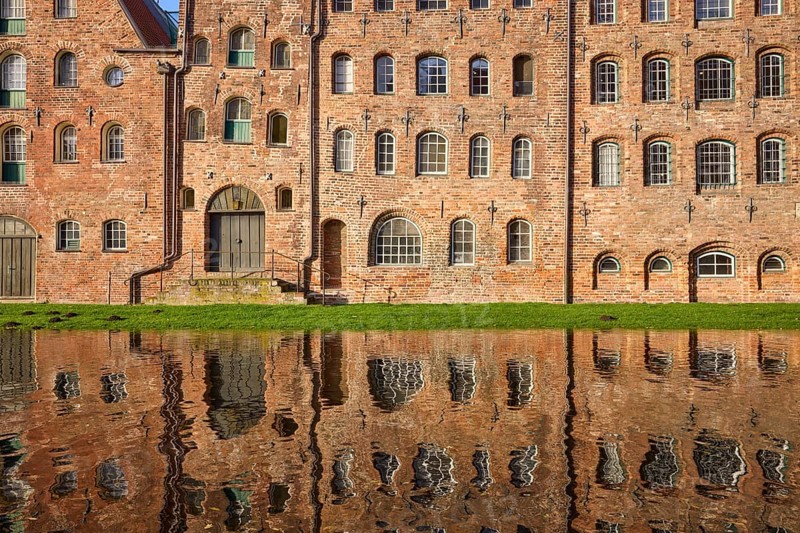 Historic salt storehouse, brick building with windows and doors, reflection on the water surface of the Trave, Hanseatic city of Lübeck, Schleswig-Holstein, Germany, Europe
