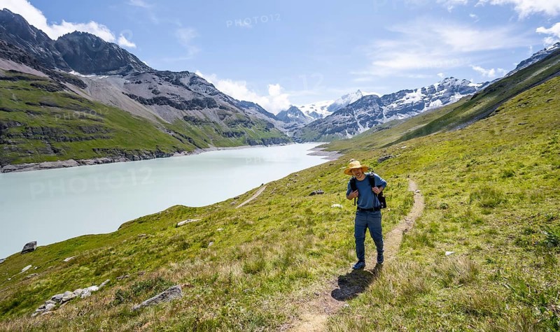 Mountaineer on a hiking trail at a blue mountain lake, Lac des Dix reservoir, Valais Alps, Valais, Switzerland, Europe