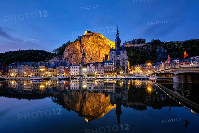 Night view of Dinant town, Collegiate Church of Notre Dame de Dinant over River Meuse and Pont Charles de Gaulle bridge and Dinant Citadel illuminated in the evening. Dinant, Belgium, Europe