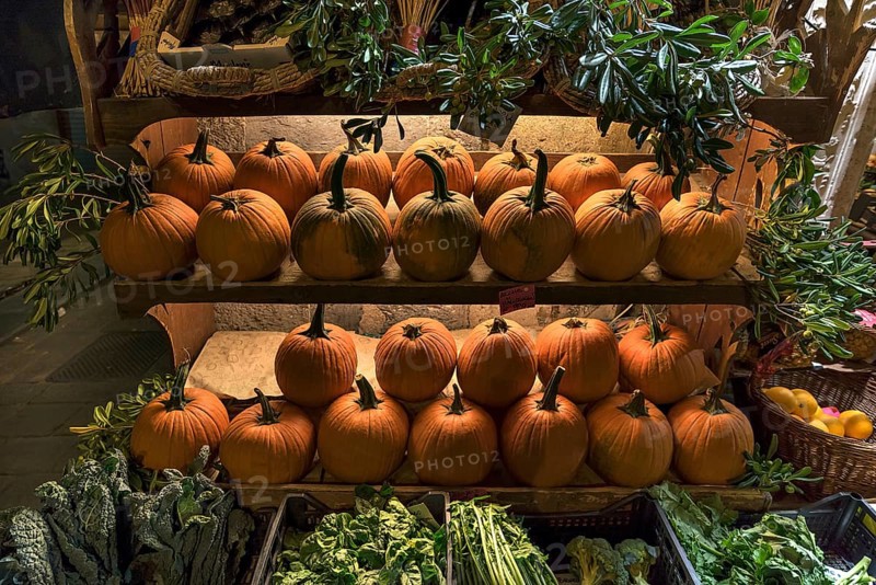 Shelves of Hokkaido pumpkins in front of a fruit shop open at night in the historic centre, Genoa, Italy, Europe
