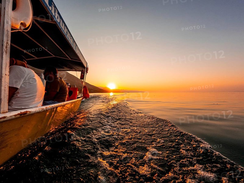 View from below along the orange sunset water of Shkoder Lake in Shiroka from a tourist boat. Albania