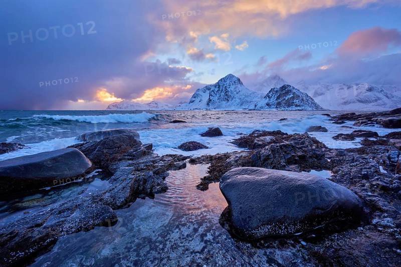 Beach of Norwegian sea on rocky coast in fjord on sunset in winter. Vareid beach, Lofoten islands, Norway, Europe