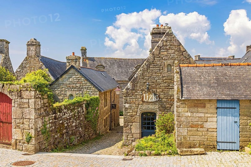 Alley in an old idyllic french villages with picturesque stone houses with lush green garden plants, Locronan, Bretagne, France, Europe