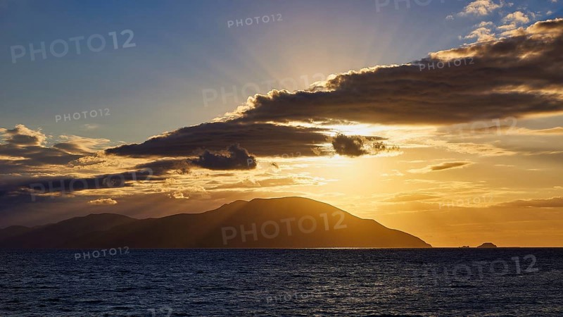 A sunset with rays bathing the sea and an island in a golden hue, sunset, Kassos, Karpathos, offshore islands, Dodecanese, Greek Islands, Greece, Europe