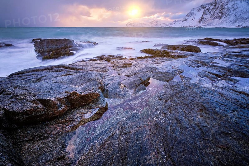 Beach of Norwegian sea on rocky coast in fjord on sunset in winter. Vareid beach, Lofoten islands, Norway, Europe