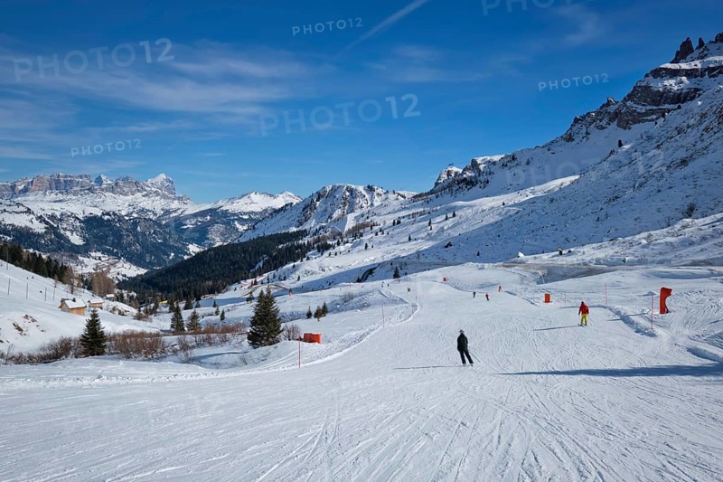 View of a ski resort piste with people skiing in Dolomites in Italy. Canazei, Italy, Europe