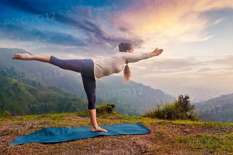 Yoga outdoors, sporty fit woman doing Ashtanga Vinyasa Yoga asana Virabhadrasana 3 Warrior pose posture in mountains