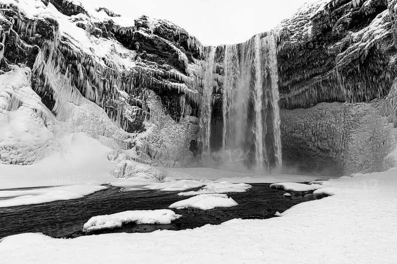 Skogafoss waterfall with icy and snowy rock face, black and white photo, Sudurland, Iceland, Europe