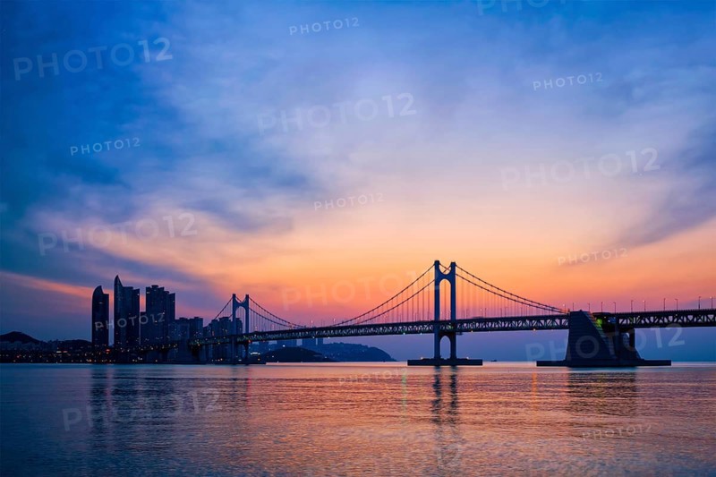 Gwangan Bridge on sunrise with skyscrapers and dramatic sky. Busan, South Korea, Asia