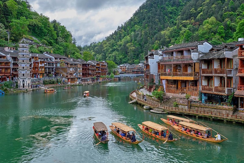 Chinese tourist attraction destination, Feng Huang Ancient Town (Phoenix Ancient Town) on Tuo Jiang River with Wanming Pagoda tower and tourist boats. Hunan Province, China, Asia