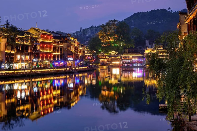 Chinese tourist attraction destination, Feng Huang Ancient Town (Phoenix Ancient Town) on Tuo Jiang River with bridge illuminated at night. Hunan Province, China, Asia