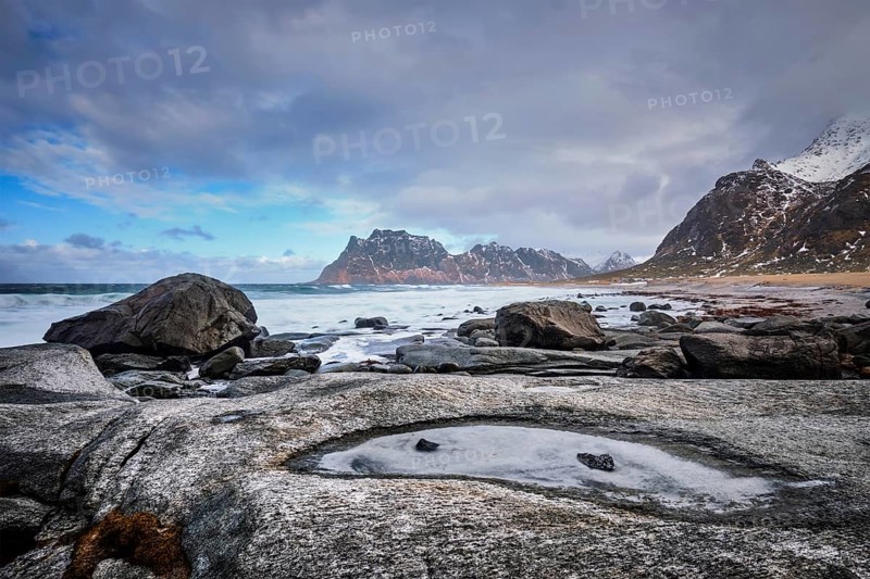 Rocks on beach of fjord of Norwegian sea in winter with snow. Utakliev beach, Lofoten islands, Norway, Europe