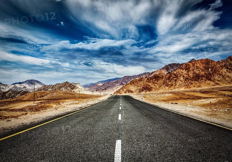 Travel forward concept background, road in Himalayas mountains and dramatic clouds. Ladakh, Jammu and Kashmir, India, Asia