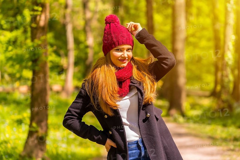 Latin girl with a black jacket, scarf and red woolen hat enjoying in an autumn park, smiling looking at camera