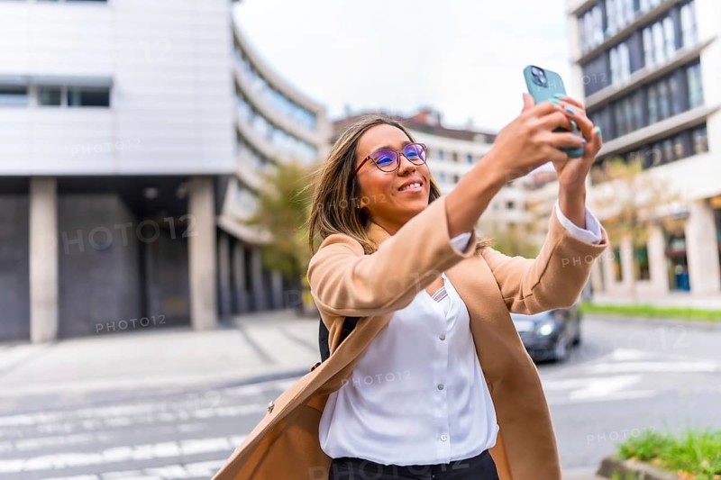 Latin woman visiting a city and taking photos with mobile phone enjoying the day in the city