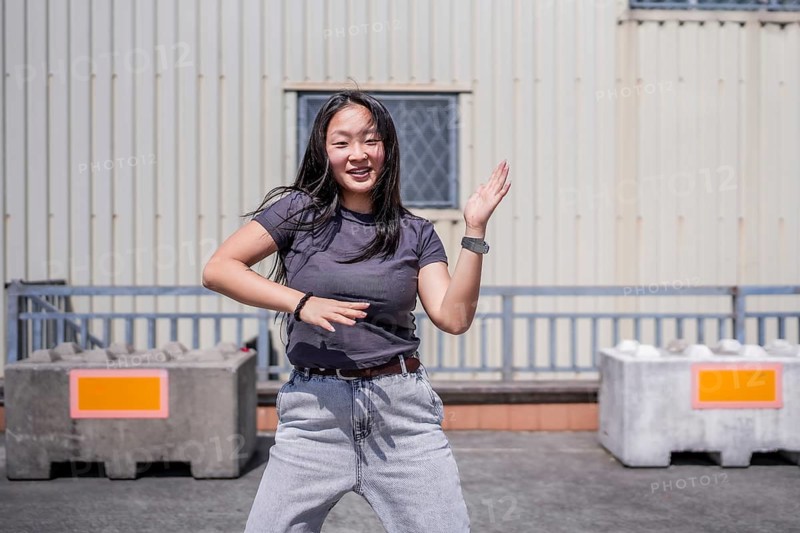 Urban female asian young dancer dancing k-pop in the city in an urban industrial space
