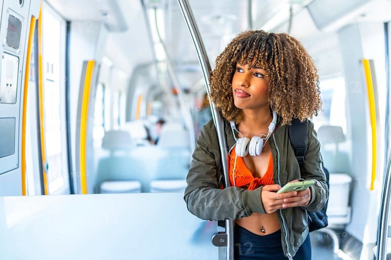 Distracted latin young beauty woman with curly hair looking away while using phone in a metro