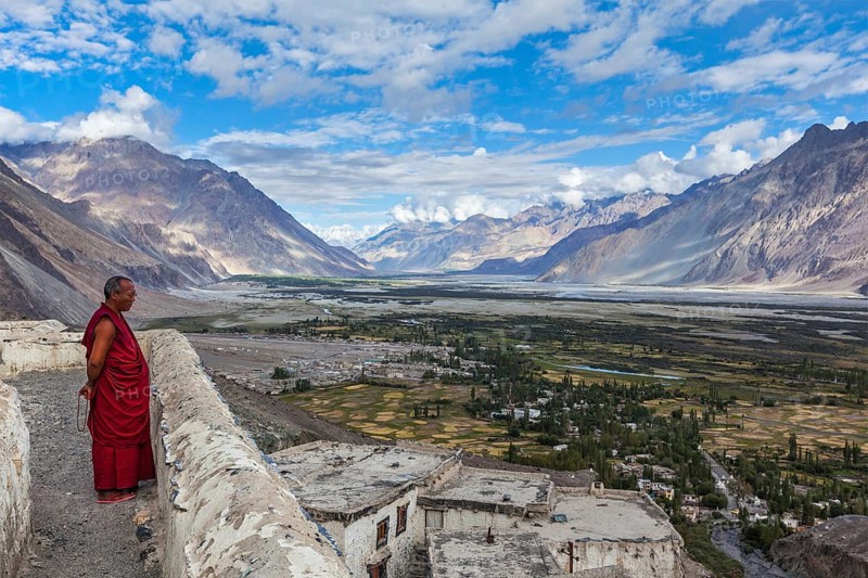 DISKIT, INDIA, SEPTEMBER 12, 2012: Unidentified Tibetan Buddhist monk praying on roof of Diskit gompa (monastery) in Himalayas, Nubra valley, Ladakh, India, Asia