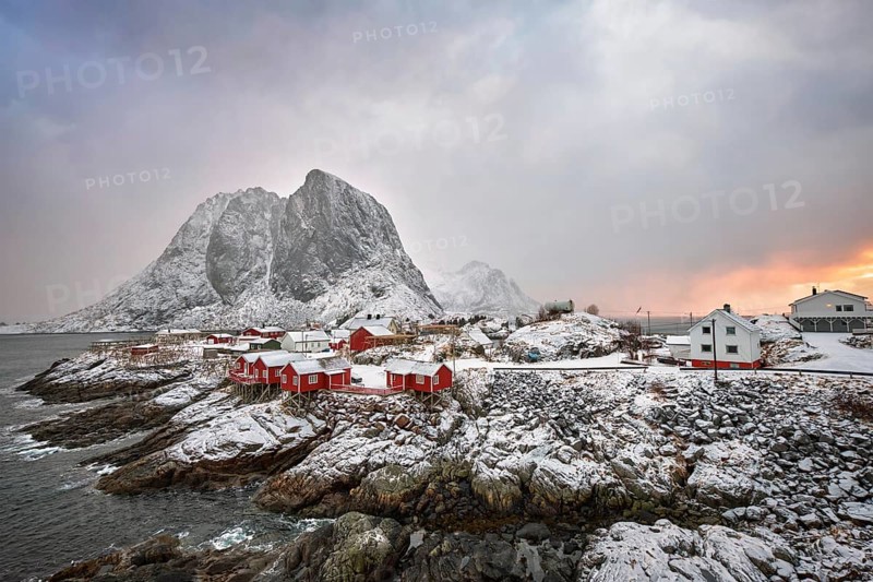 Famous tourist attraction Hamnoy fishing village on Lofoten Islands, Norway with red rorbu houses. With falling snow in winter on sunrise