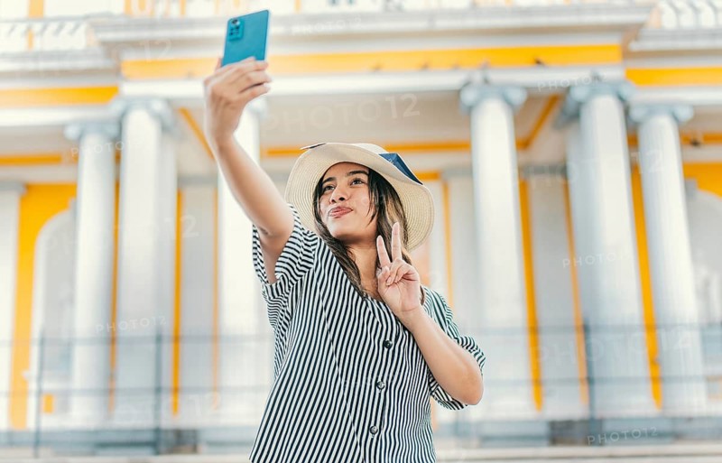 Beautiful tourist girl taking selfie in the cathedral of Granada. Young tourist woman with hat taking selfie in a square. Selfies and vacation concept