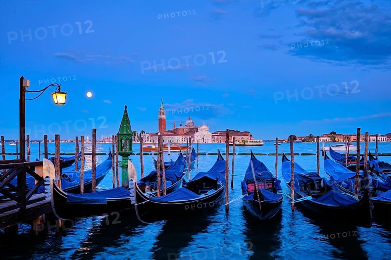 Romantic vacation Venice travel background, gondolas at Saint Mark (San Marco) square and Basilica San Giorgio Maggiore Church seen across Venice lagoon with full moon. Venice, Italy, Europe