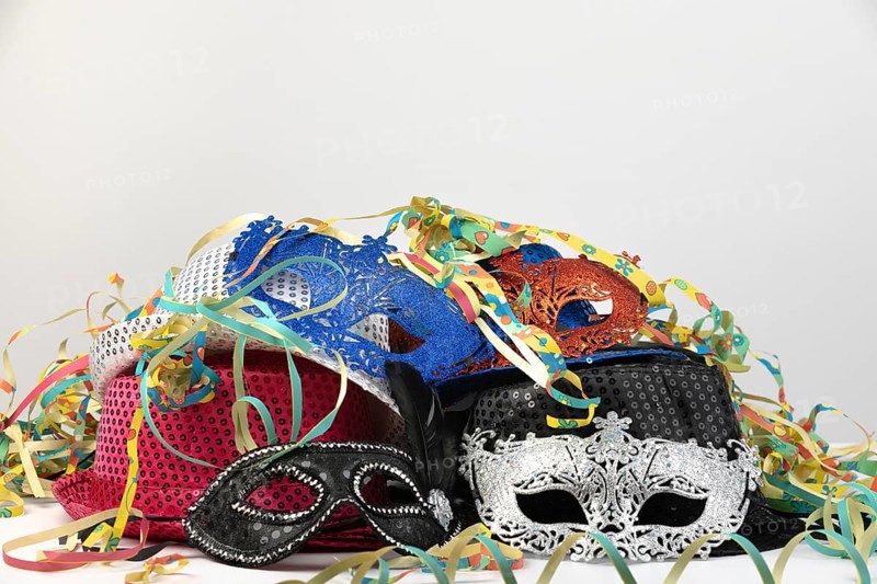 Various carnival masks and hats, surrounded by colourful streamers, carnival
