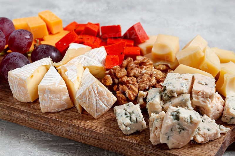 Assorted cheese on a wooden board, with grapes and walnuts, appetizer, no people