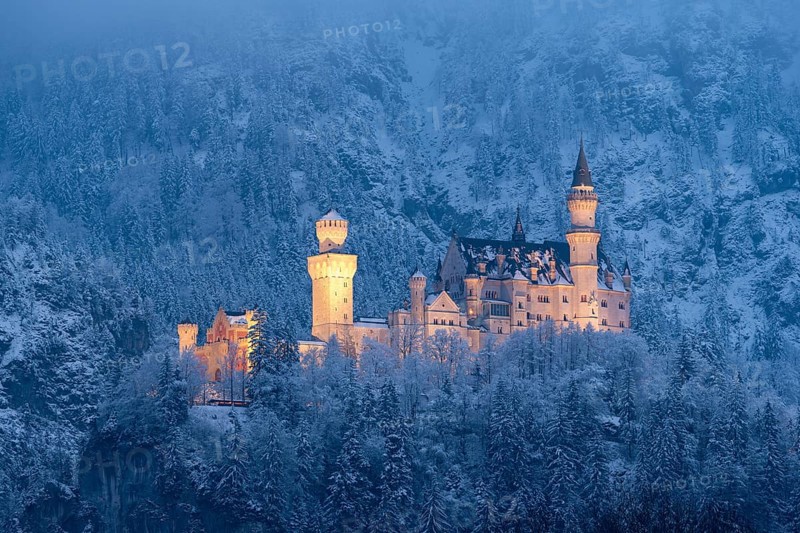 A majestic, illuminated castle in the middle of a snow-covered mountain landscape at night, Neuschwanstein, Schwangau, Ostallgäu, Allgäu, Swabia, Upper Bavaria, Bavaria, Germany, Europe