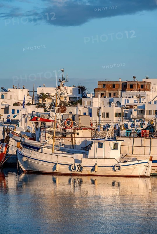 Fishing boats in the harbour at sunset, reflected in the sea, White Cycladic houses, Naoussa, Paros, Cyclades, Greece, Europe