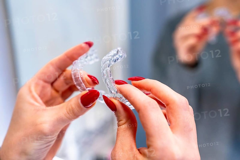 Close-up of a hands of a caucasian woman holding an invisible aligner in the toilet
