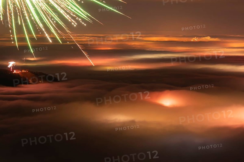 New Year's Eve fireworks 2024 and a little red Aurora Borealis Northern Lights. On the Breitenstein, Swabian Alb near Ochsenwang. Sea of fog in the foothills of the Alb. View towards Stuttgart. In the foreground, the Hörnle near Teck looks out of the fog
