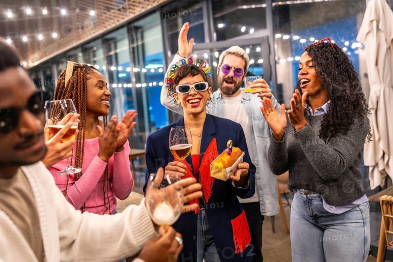 Happy woman celebrating birthday with multiracial friends at bar in the night
