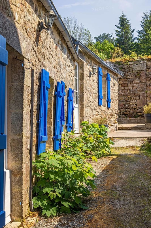 Narrow alley in an old idyllic French villages with picturesque stone houses and blue window shutters, Locronan, Bretagne, France, Europe