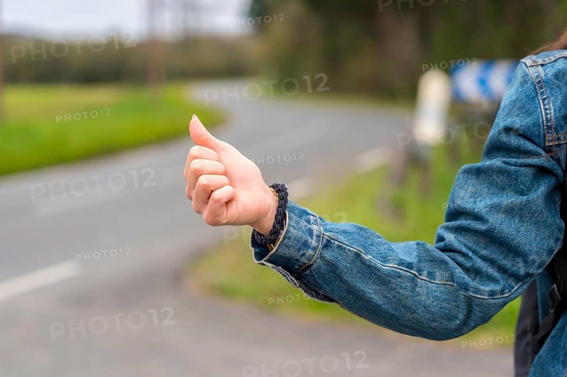 Close-up photo of the hand of a woman hitchhiking in a rural road