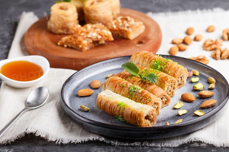 Set of various traditional arabic sweets: baklava, kunafa, basbus in ceramic plates on a gray concrete background. side view, selective focus