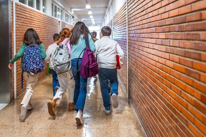 Elementary school students joyfully running down the hallway after the class bell rings, filled with energy and excitement for recess