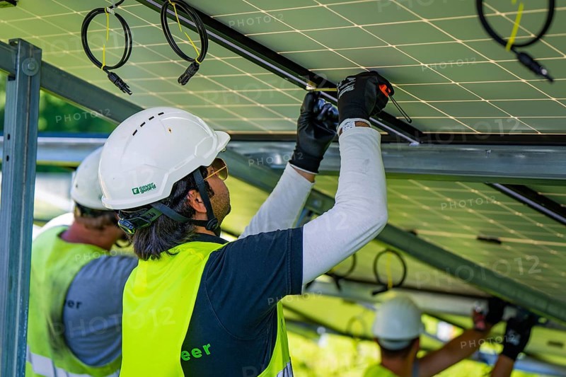 Workers install solar panels wearing safety helmets and high-visibility waistcoats, construction of Black Forest Nature solar park, Weil der Stadt, Germany, Europe