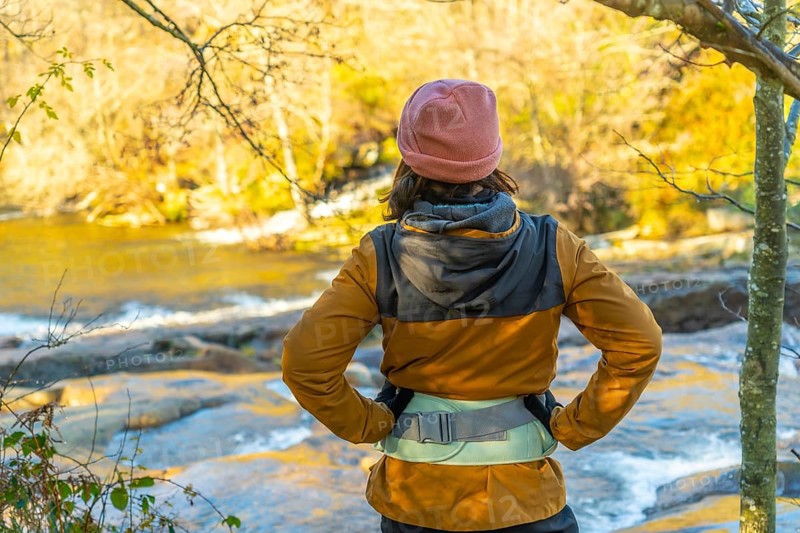 Hiker admiring the serene zaldibartxo pool in gorbeia natural park on a sunny autumn day, surrounded by vibrant foliage and tranquil nature
