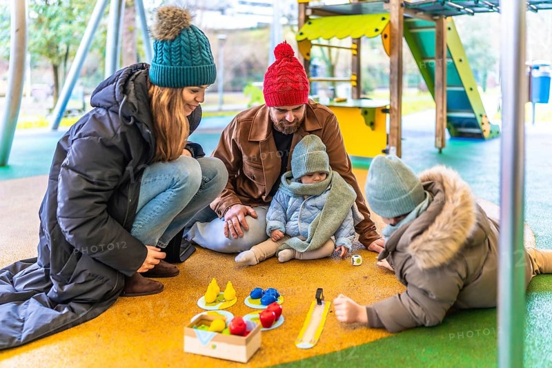Happy family enjoying quality time together, playing board game at an outdoor playground during winter season