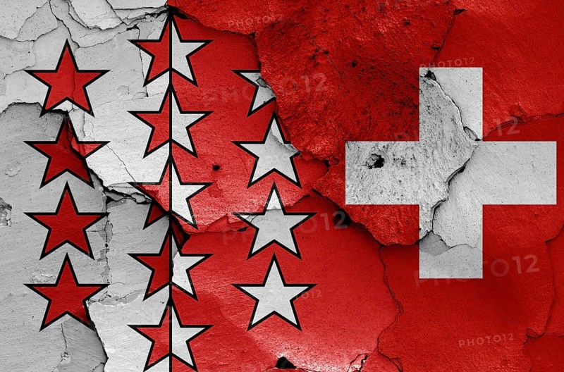 Flags of Valais canton and Switzerland painted on cracked wall