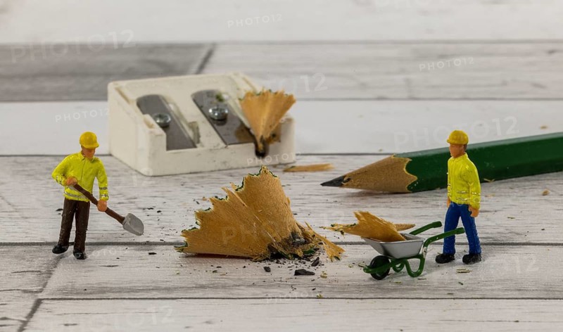 Little figures from little world cleaning up the mess of the mess of the pencil sharpener