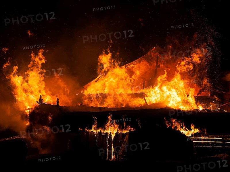 Arson or nature disaster, burning fire flame on wooden house roof