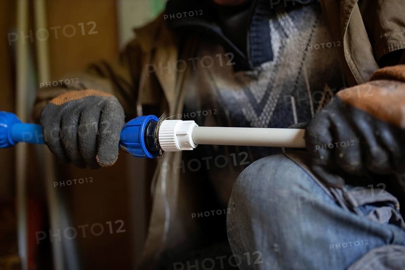Close-up of gloved hands adjusting a pipe fitting